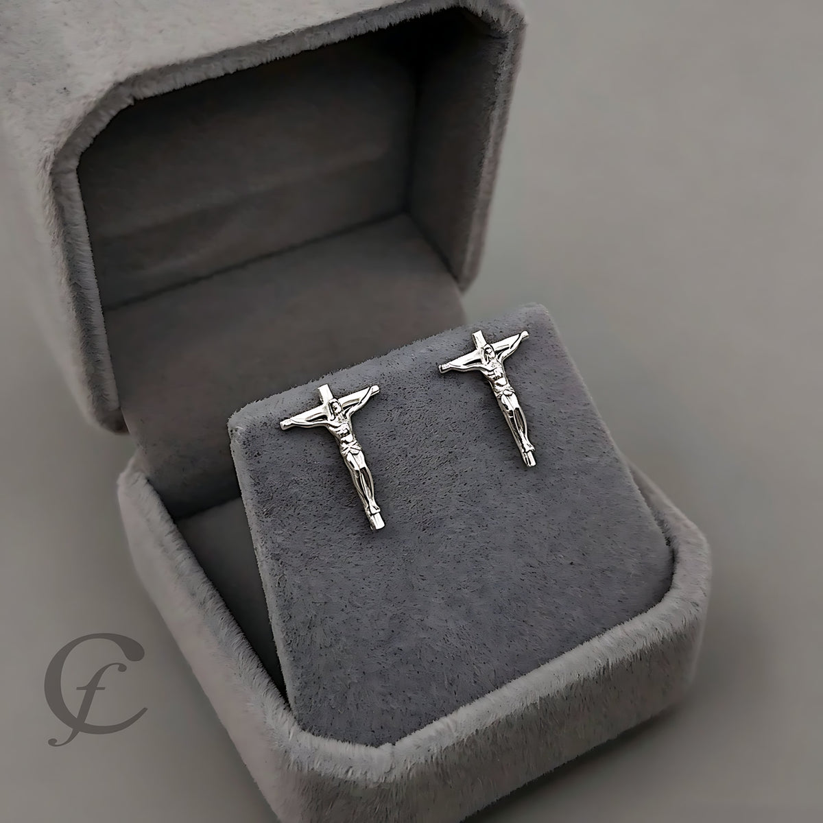 Silver crucifix earrings in a gray jewelry box