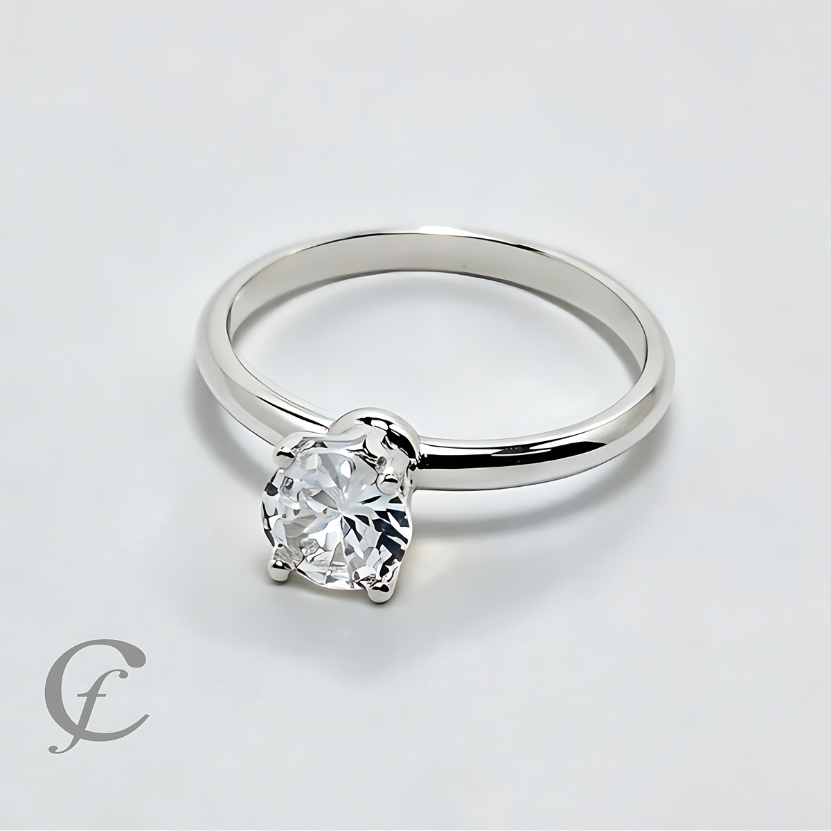 A classic solitaire engagement ring featuring a round brilliant-cut clear gemstone in a four-prong setting on a polished silver-colored band, set against a clean white background.
